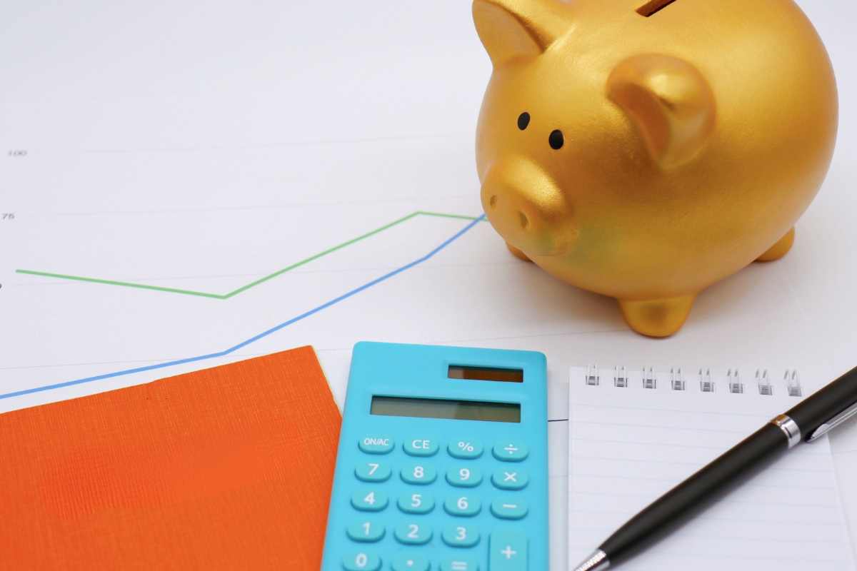 calcolatrice, carta e penna e porcellino come salvadanaio