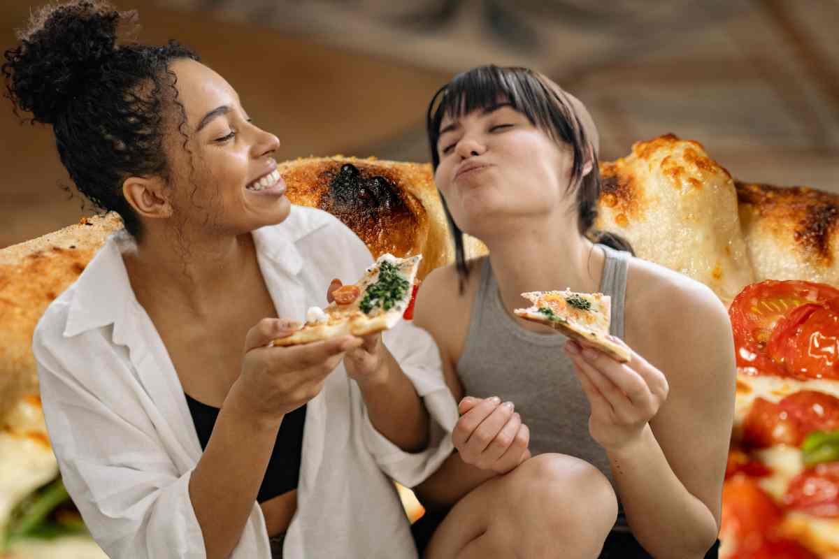 donne mangiano pizza e alle spalle una pizza