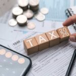 mano che tiene scritta tassa in legno, calcolatrice e soldi