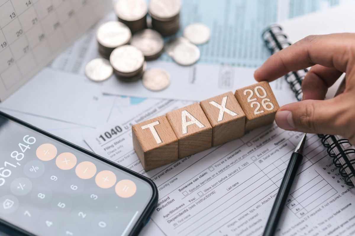 mano che tiene scritta tassa in legno, calcolatrice e soldi