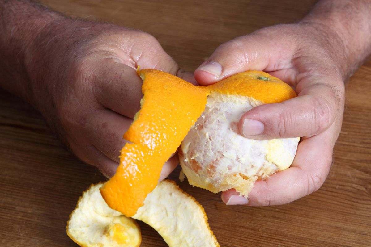 persona che sbuccia arancia con le mani