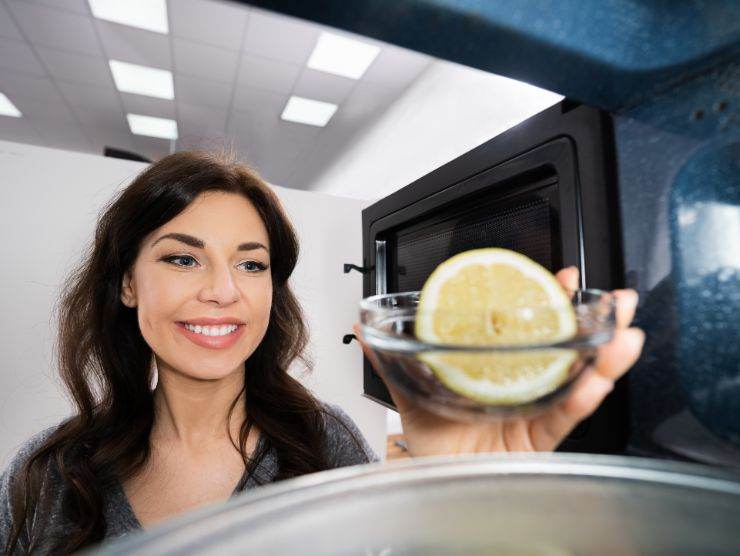 donna che inserisce ciotola con acqua e limone nel microonde